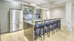A modern kitchen with a central island, stainless steel appliances, and a seating area with bar stools. - 101 Verbier Building 5 (Mont-Tremblant)