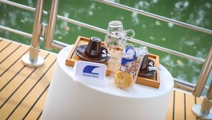 A table with a coffee setup, a glass mug, and a sign on a boat deck.