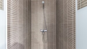 Ducha con cabezal de ducha de mano y grifo empotrado en un baño con azulejos.