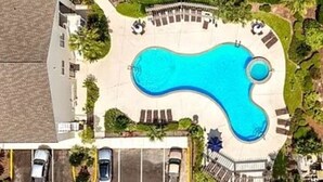 An aerial view of a swimming pool with lounge chairs and a parking area.