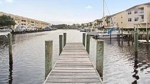 A wooden pier leading to a marina with boats, surrounded by buildings.