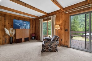 Un intérieur en bois avec une télévision, un canapé et une grande fenêtre.