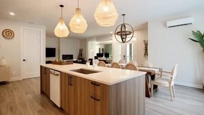 A modern kitchen with wooden cabinets, a central island, and pendant lighting.