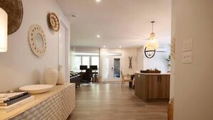 A modern living room with a sofa, a coffee table, and a dining area with a table and chairs.