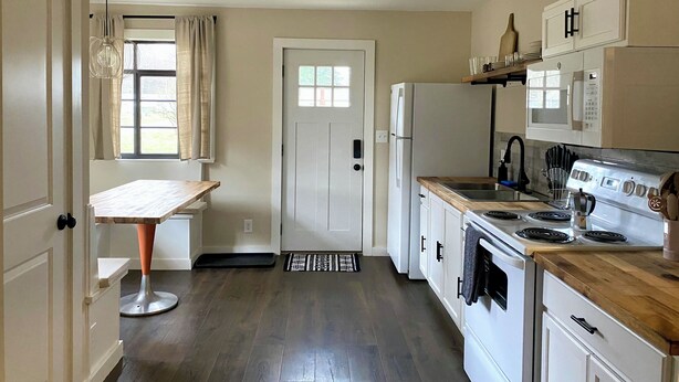 A kitchen with a refrigerator, stove, microwave, and wooden countertop.