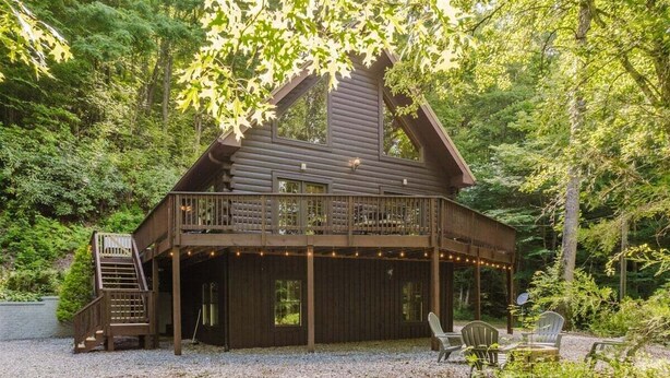 Een chalet met balkon, buitenmeubels en een trap naar een hoger gelegen niveau.
