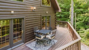 Een houten chalet met terras, grote ramen en een tafel met stoelen.