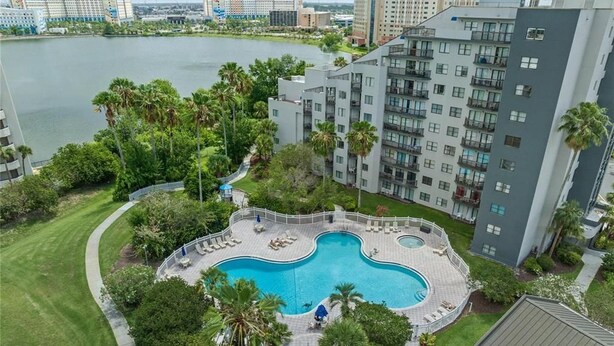 Un edificio de gran altura con piscina rodeado de vegetación y vistas a un cuerpo de agua.