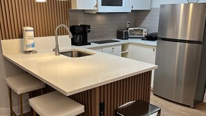Una cocina moderna con una isla central, electrodomésticos de acero inoxidable y un bote de basura empotrado.