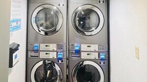 Un lavadero con dos lavadoras apiladas de carga frontal y un dispensador de papel en la pared.
