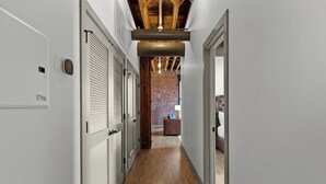A hallway with wooden floors, white walls, and a brick wall in the background. - DWTN Riverfront Loft W/D Gated Parking (St. Louis)