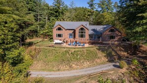 A two-story house with a large deck, surrounded by dense forest. - Modern Smoky Mountain Cabin for Big Views, Lake Days, and Hot Tub Nights (Bryson City)