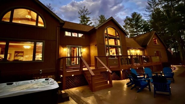 A wooden cabin with a hot tub, outdoor seating, and a covered deck. - Modern Smoky Mountain Cabin for Big Views, Lake Days, and Hot Tub Nights (Bryson City)