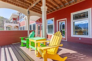 Relax on the covered outdoor deck with a table and two chairs, surrounded by the building's multiple windows.
