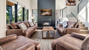 A modern living room with leather sofas, a wooden coffee table, a fireplace, and a staircase. - NEW Heated Pool & Theater Luxury Getaway|Mtn Views (Sevierville)