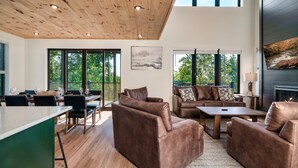 A spacious living area with a wooden ceiling, large windows, and a fireplace. - NEW Heated Pool & Theater Luxury Getaway|Mtn Views (Sevierville)