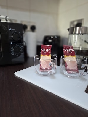 Dois copos de café latte Costa em um suporte branco em uma cozinha.