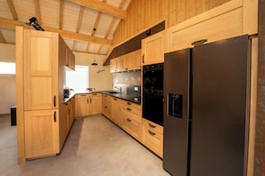 A modern kitchen with wooden cabinets, a stainless steel refrigerator, and a built-in oven.