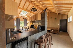 A modern kitchen with a central island, bar stools, and a dining area with a table and chairs.