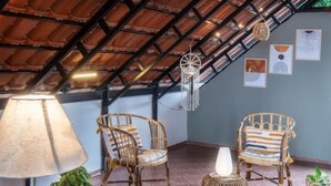 Une pièce chaleureuse avec un plafond en pente, des meubles en osier et un tapis coloré tissé.