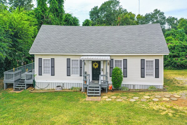 A two-story house with a front porch, a staircase, and a small front yard with stepping stones. - Lumberjack Hideaway Near Campus in Nacogdoches! (Nacogdoches)