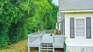 A wooden deck leading to a house with a gray roof and white siding.