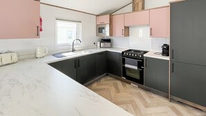 A modern kitchen with a sink, stove, and microwave. - 2 bedroom accommodation in Southerness (Southerness)