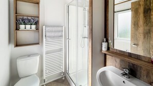 A bathroom with a toilet, a shower, a sink, and a mirror. - 2 bedroom accommodation in Southerness (Southerness)
