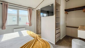 A bedroom with a bed, a wardrobe, a desk, and a window. - 2 bedroom accommodation in Southerness (Southerness)