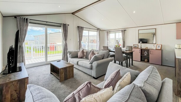 A spacious living area with a balcony, a dining table, and a TV stand. - 2 bedroom accommodation in Southerness (Southerness)