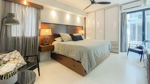 Una camera d'albergo moderna con un letto, lampade sui comodini, una ventola a soffitto e vista all'esterno.