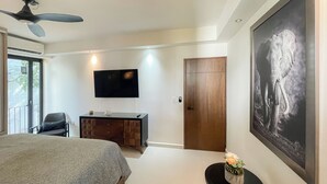 Una camera da letto con un letto, una scrivania, un televisore, una porta e un grande quadro raffigurante un elefante.