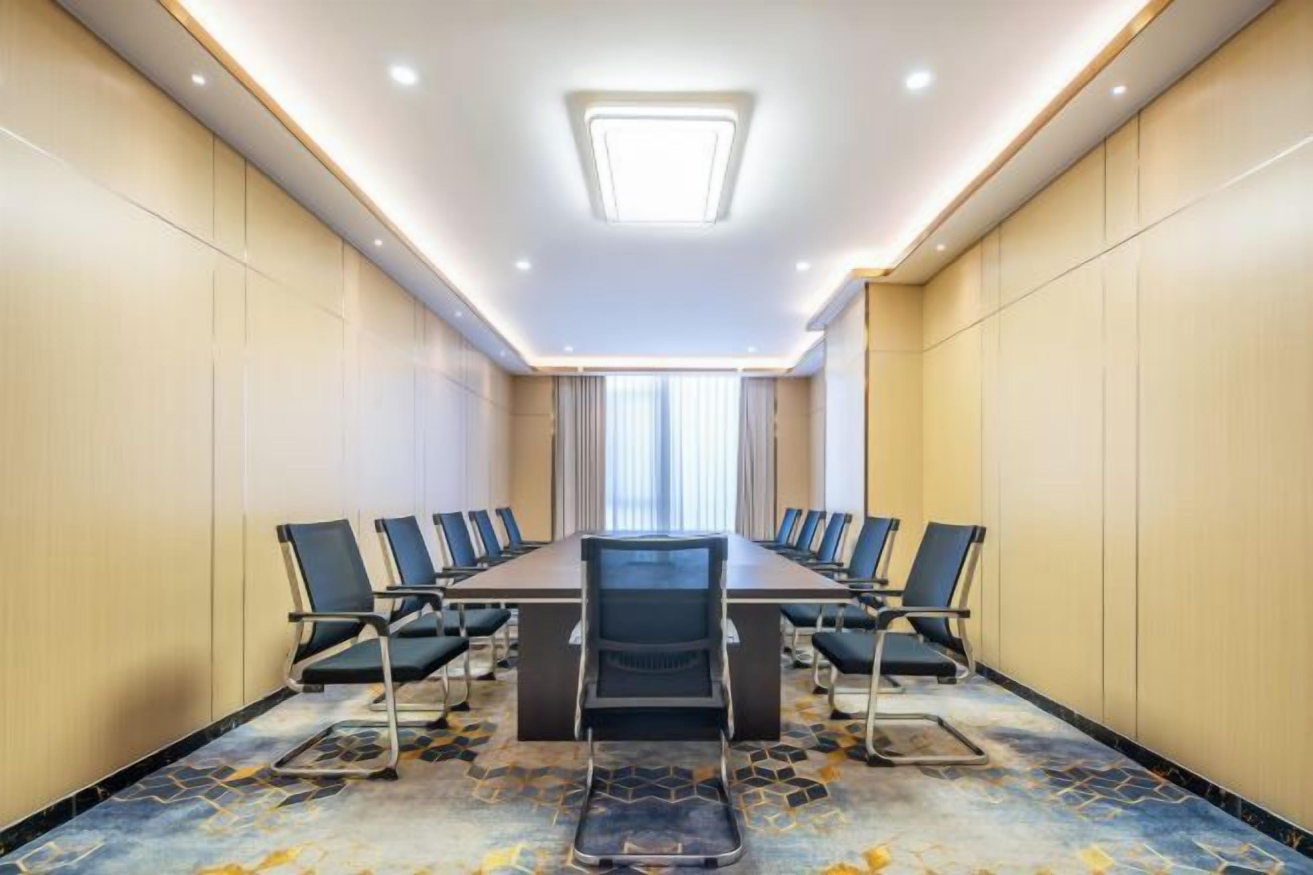 Una sala de conferencias con una larga mesa, sillas y piso alfombrado.