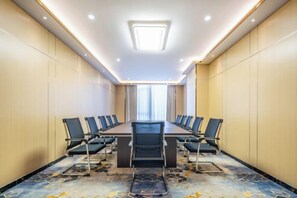 Une salle de conférence avec une longue table, des chaises et un sol recouvert de moquette.
