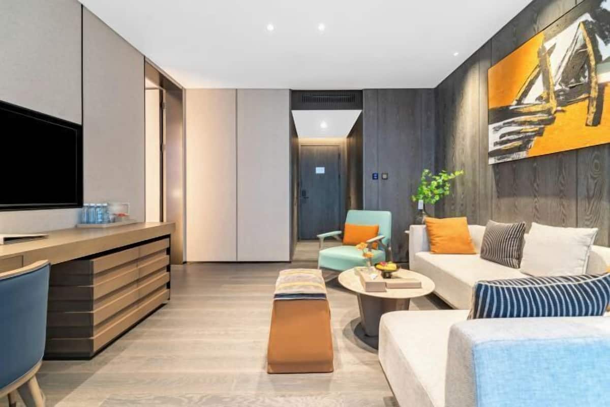 Een moderne woonkamer met een flatscreen televisie, een bank, een salontafel en een eethoek met een bankje.