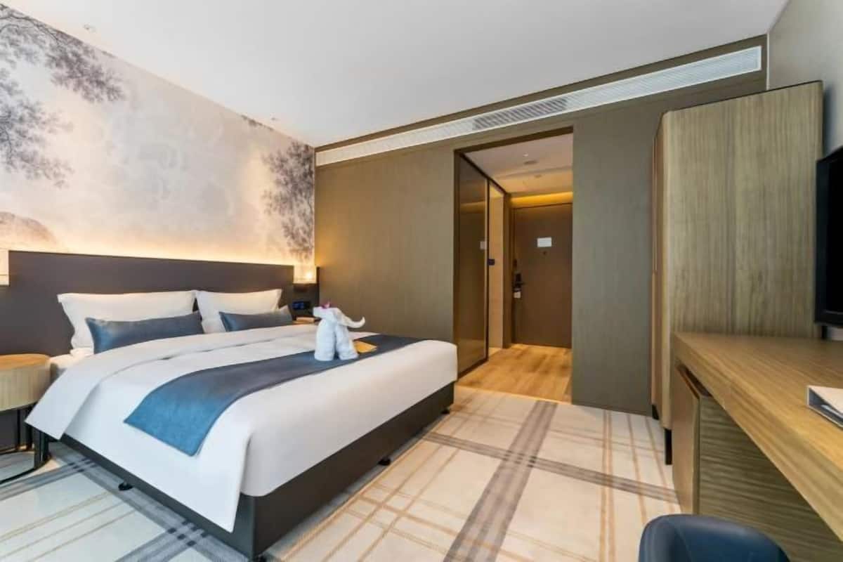 Een moderne hotelkamer met een groot bed, een bureau en een televisie.