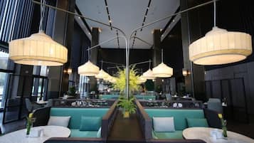 Un interior moderno con zonas de estar, iluminación colgante y una planta central.