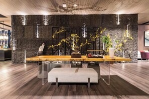 Een modern interieur met een stenen muur, een houten tafel en transparante glazen stoelen.