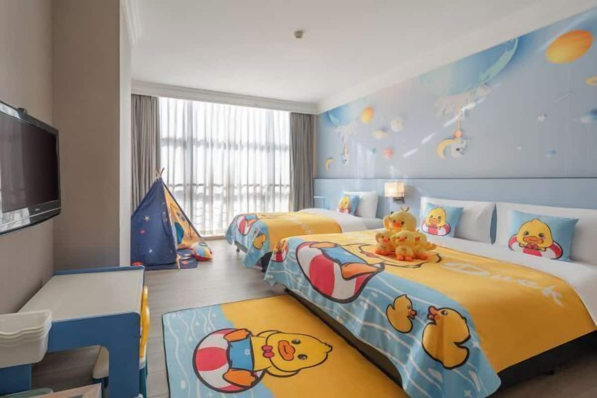 Een hotelkamer met twee bedden, een televisie, een bureau en een raam met gordijnen.