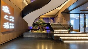 Ein modernes Interieur mit einer geschwungenen Treppe, einem Empfangstresen und einem Schild mit beleuchteter Beschriftung.