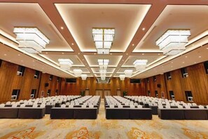A conference room with rows of chairs, a patterned carpet, and a modern ceiling design. - Nishi Haitai Hotel (Jinan)