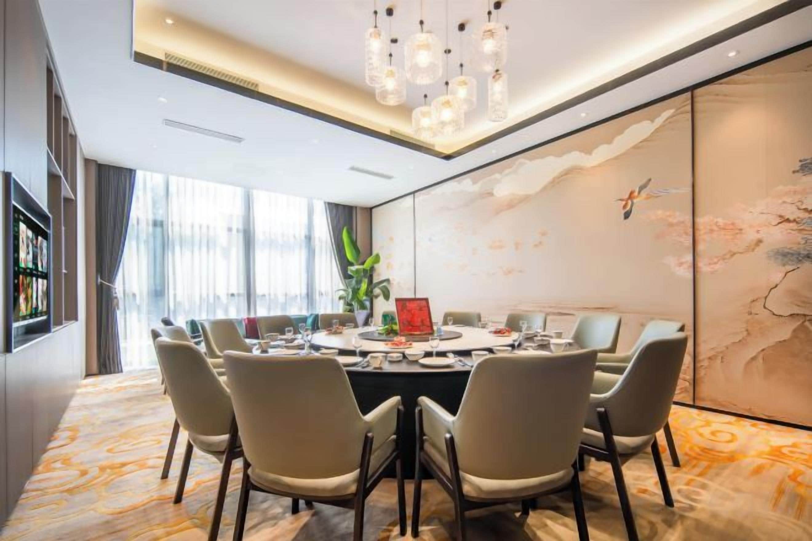 A modern dining room with a round table, six chairs, and a chandelier.