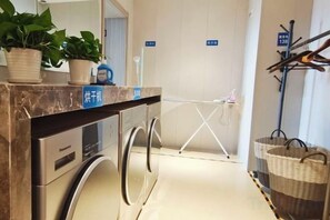 Habitación de hotel con lavadora, tendedero y una planta en la encimera.