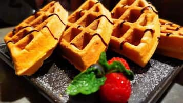 A tray of waffles with chocolate drizzle and a strawberry.