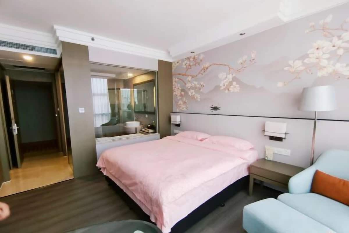 Een slaapkamer met een bed, nachtkastje, lamp en een bloemen behang muur.