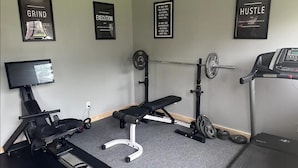 A home gym with a treadmill, weight bench, and barbell. - Seneca Hideaway/Rustic Hunter’s cabin/Hot Tub (Geneva)
