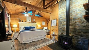 Un dormitorio acogedor con cama, lámparas de noche, chimenea y paredes de madera.