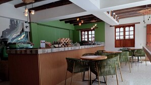 Un restaurant doté d’un mur végétal, d’un bar en bois et de chaises vertes.