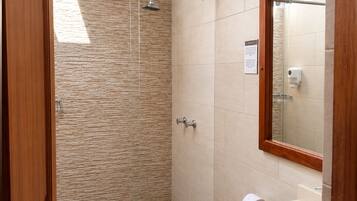 A bathroom with a shower, toilet, and sink, featuring stone wall tiles and wooden beams.
