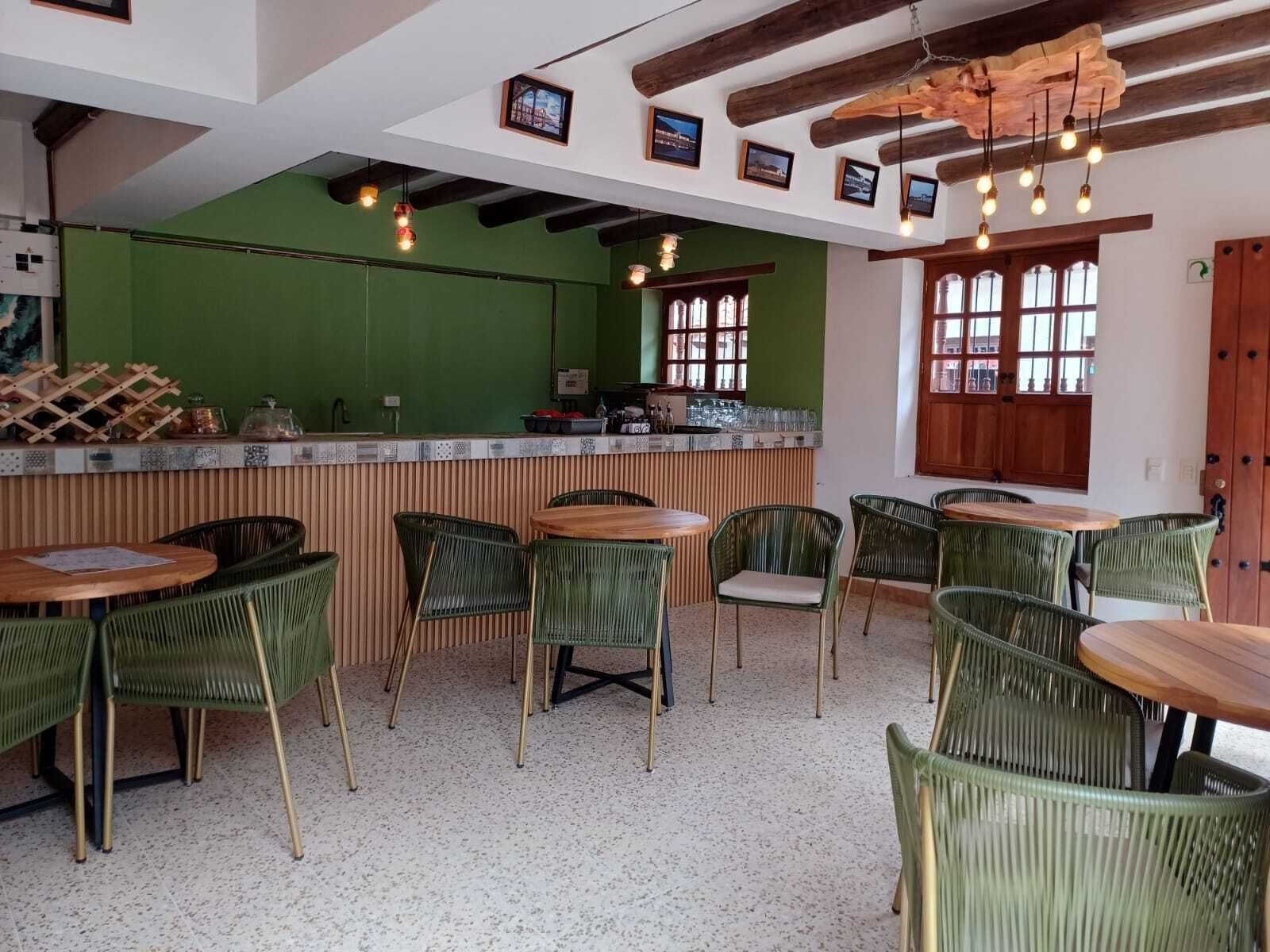 A restaurant interior with green walls, wooden tables, and wicker chairs.